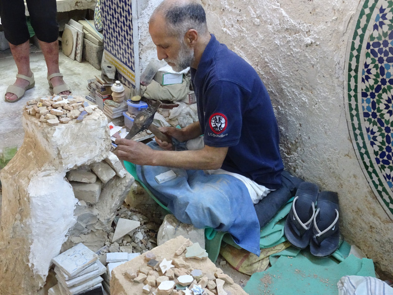 Man making mosaic pieces