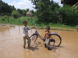 Boys fixing a bike in big puddle