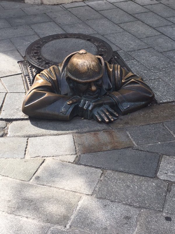 Sculpture of man emerging from manhole