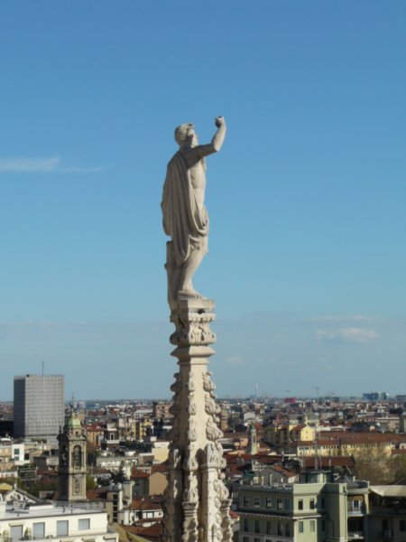 A Statue on top of the Cathedral sheilding his eyes from the glare of the sun