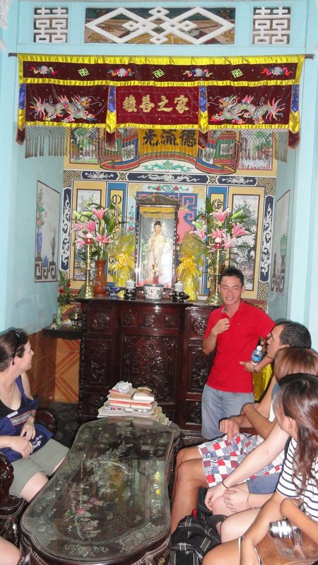 Ky explaining the typical Vietnamese household items, including a Buddhist deity and urns of those past