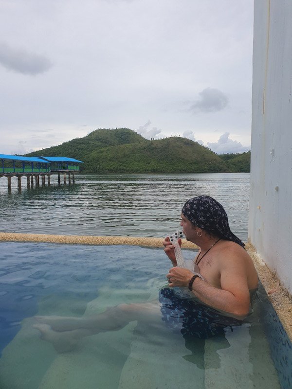 Ukulele playing in the infinity pool overlooking the ocean and island