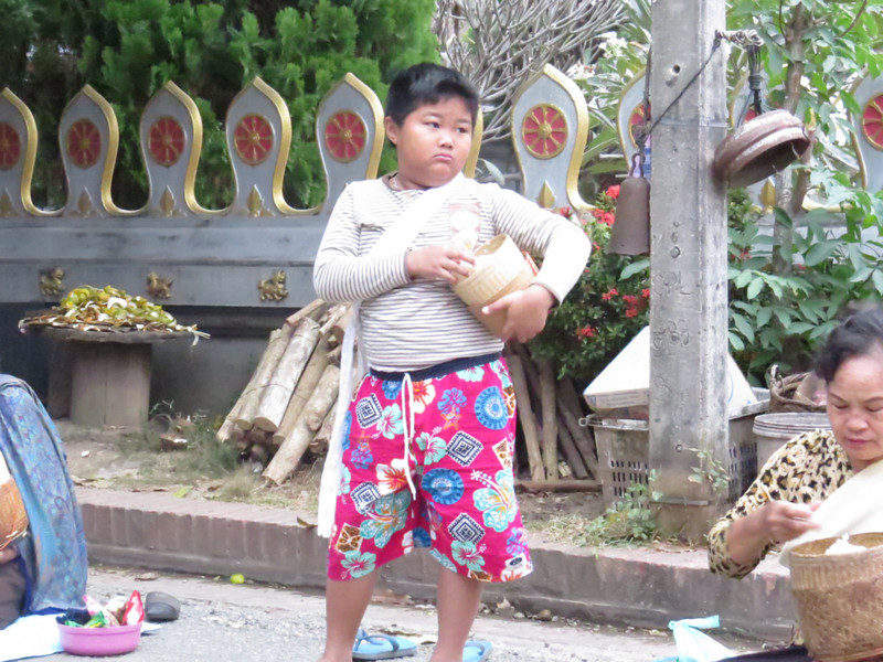 A local boy with his bowl of rice to donate.
