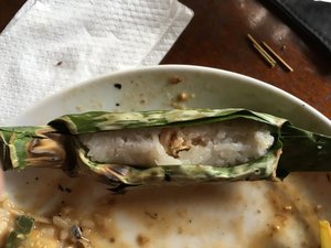Sticky rice and chicken pieces wrapped in leaves, opened