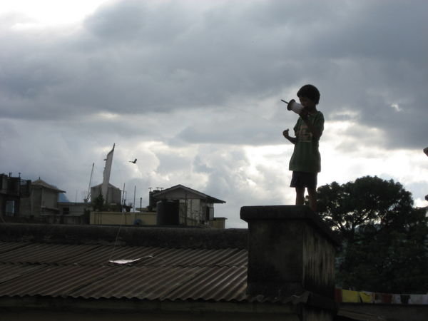 Boy flying a kite on the rooftop in Kathmandu