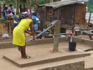 A lady pumping water to bring home