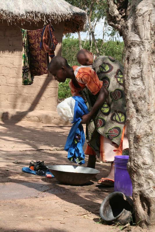 a mother washing clothes while caring for her child