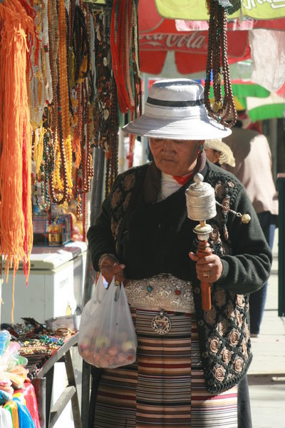 Old lady spins prayer wheel whilst shopping