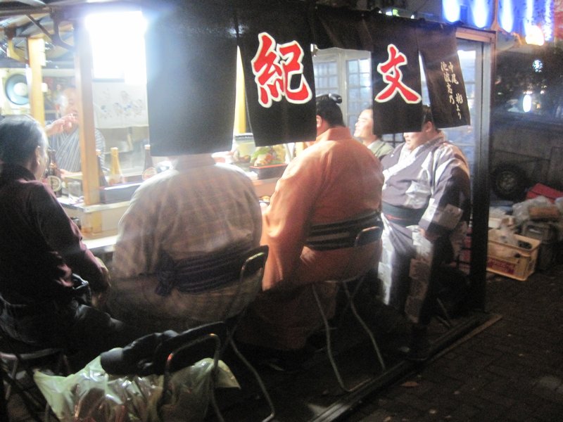 Sumo wrestlers eating at one of the street stalls (yatai)