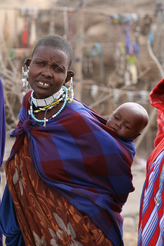 Masai women with her baby tightly wrapped on her back