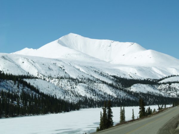 Snow covered mountain and river along Alaska Highway