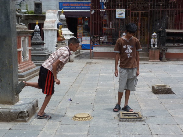 Chavales nepalis jugando con una moneda en un templo