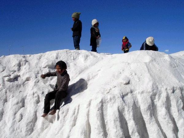 Children sledge down a mound of salt, using plastic bottles!