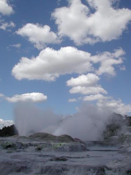 Steam from Pohutu Geyser merges with the clouds.