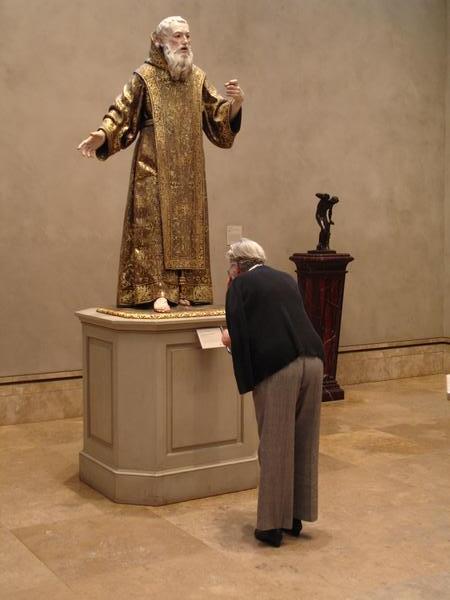 A woman bowing down to read about a saint
