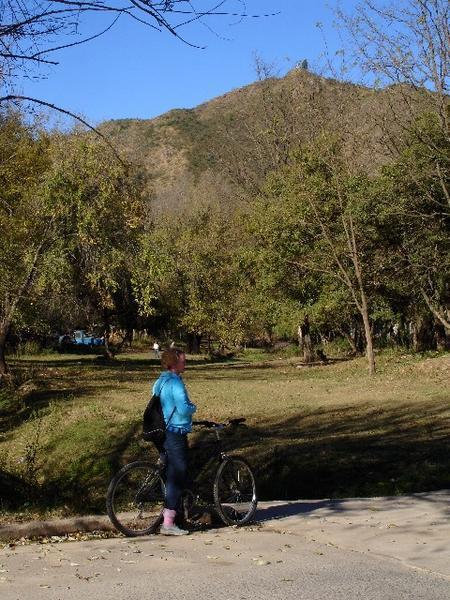 Denise on bike with the Trail of the Virgin in the background.