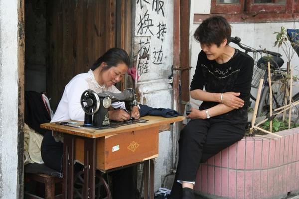 Seamstress hard at work while having a chat with her friend