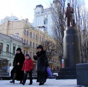 A family walks past a statue of Vladimir Lenin.