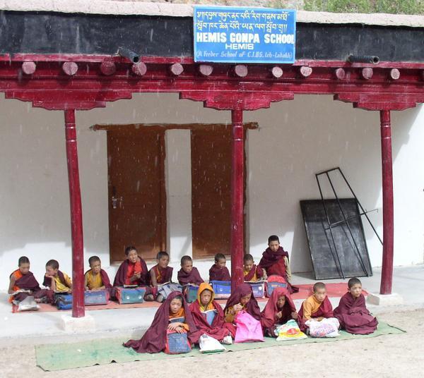 Novice monks sit outside in the rain while others take cover, Hike back to Hemis Gompa