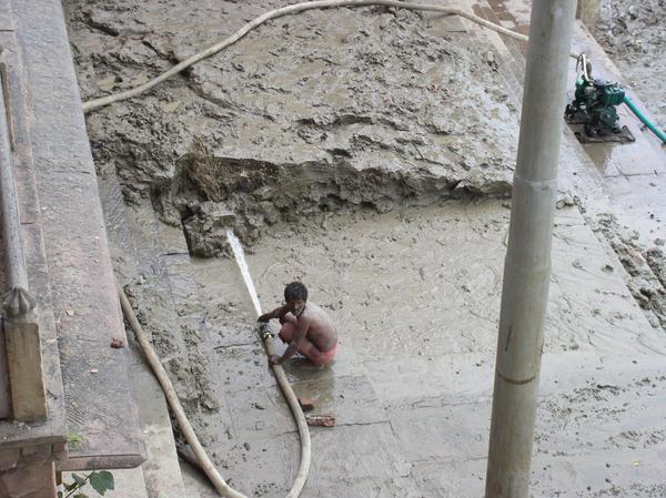 Worker clears teh piled up mud, Varanasi