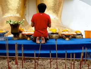Thai man praying at feet of Buddha