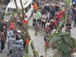 Angry villagers brandishing sticks block the road by the crashed minibus