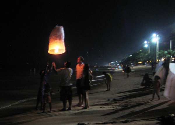 Lighting the miniature hot air balloons for Loy Krathong Festival