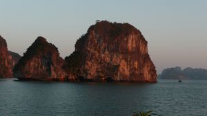 The sun sets against the rocks in Halong Bay