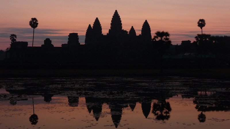 The sun slowly rises behind Angkor Wat