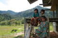 Some Kelabit children on the steps of a barn near some wet paddy