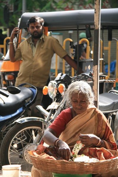 Typical street scene - lady stringing Jasmine and Rickshaw driver