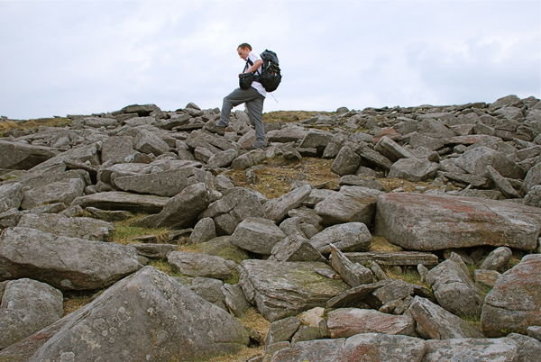 Steve clambering over the boulders at the top of Little Dun Fell. Pennine Way, Cumbria
