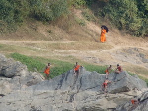 Older monk passing as young monks play in river