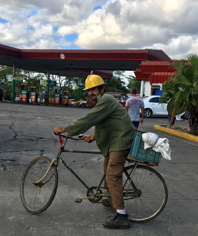 Old man picking up cans at fuel station. 
