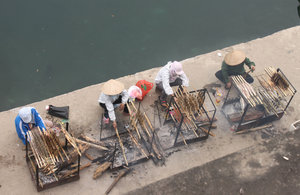 Women are baking fishes outside a temple