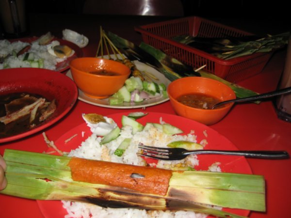 Traditional satay skewers and fish paste wrapped in a bamboo leaf
