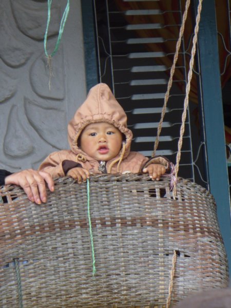 Cute baby in swinging crib on the veranda of our tea house