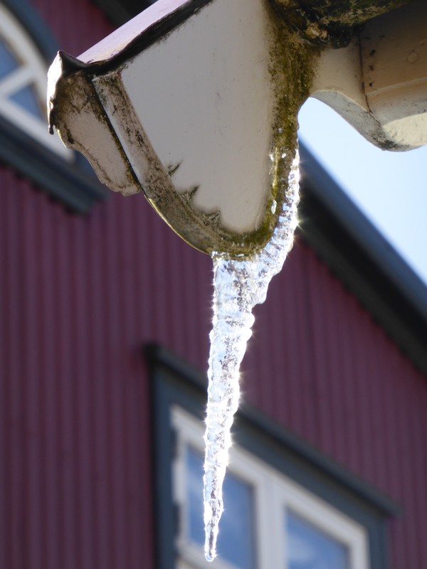 Icicle dripping down from the guttering glistening in the sunlight