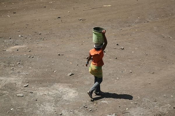 Female construction worker carrying a 20 litre bucket of water