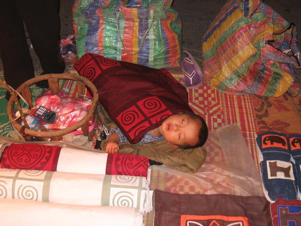 Petit enfant qui dort dans le marché pendant que maman travaille