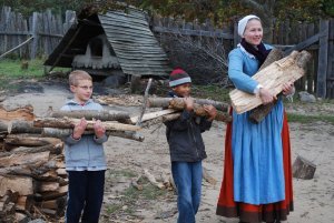 Kids helping a costumed guide collect firewood