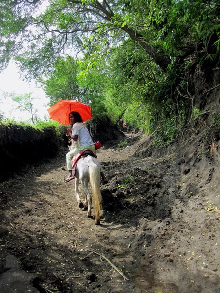 Local woman riding up the path to the volcano