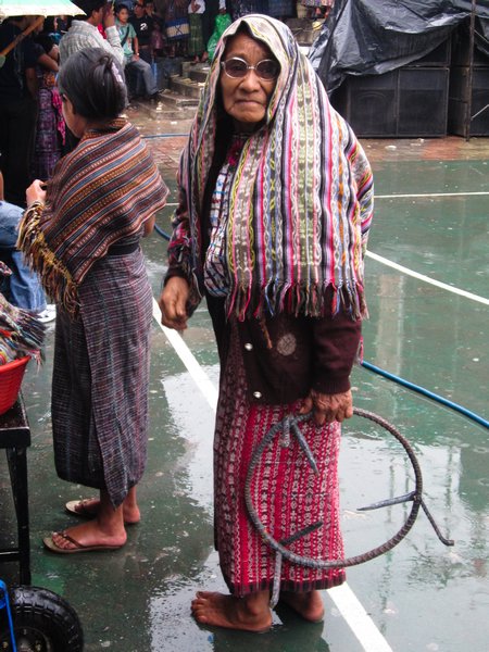Barefoot old woman in traditional dress in the rain in San Pedro, Lake Atitlan