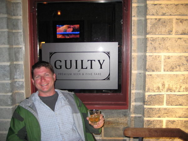 Alex in front of Guilty Sign in Queenstown