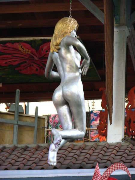 Naked silver woman suspended from a tree