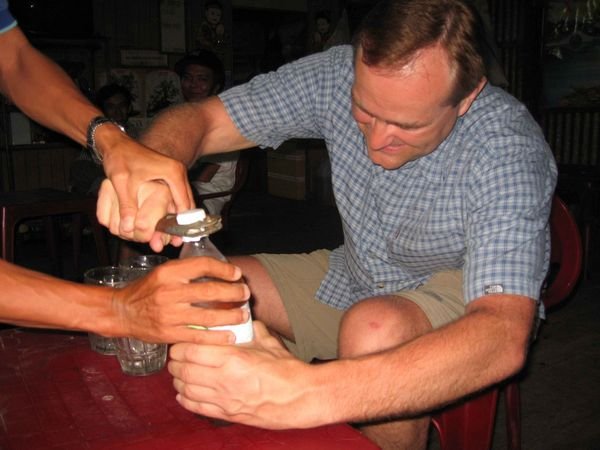 Chris trying to open homebrewed beer in Chau Doc