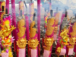 Large colourful incense sticks burning outside Chinese Temple. 