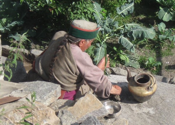Old lady washing dishes in Chitkul
