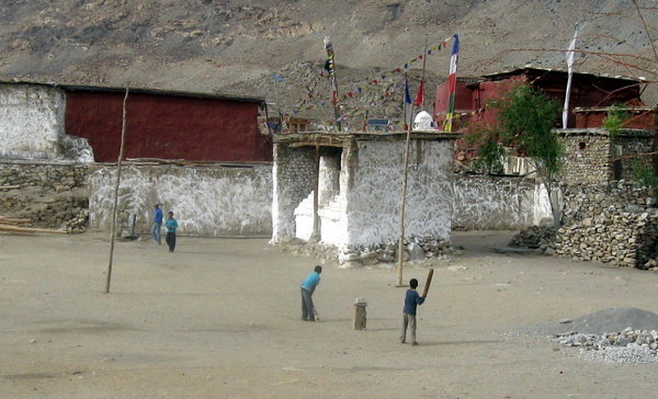 Boys playing cricket in the temple grounds