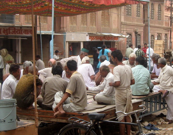 Men playing cards on raised platform in city streets